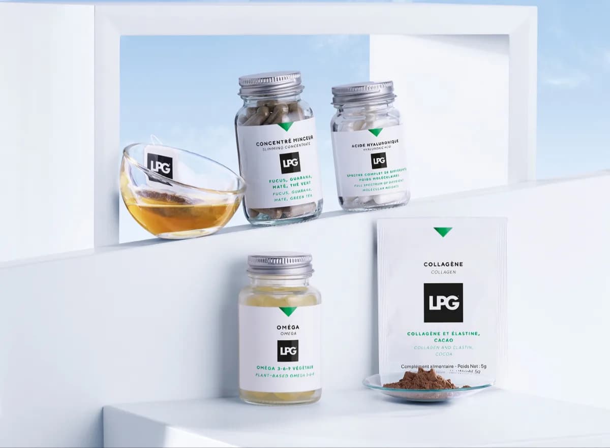 Die Nahrungsergänzung von LPG: Kapseln in Glasdosen, eine Tasse Kräutertee und ein Beutel Kollagenpulver mit Kakao